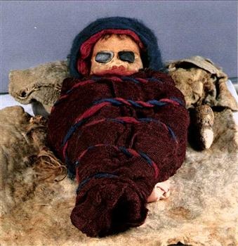 扎滚鲁克墓地婴儿干尸：1985 年出土，距今约 2800 年，身高约 66 厘米，棕色头发，头顶有红毛线辫，身体用红色和花色扎染毛布包裹。