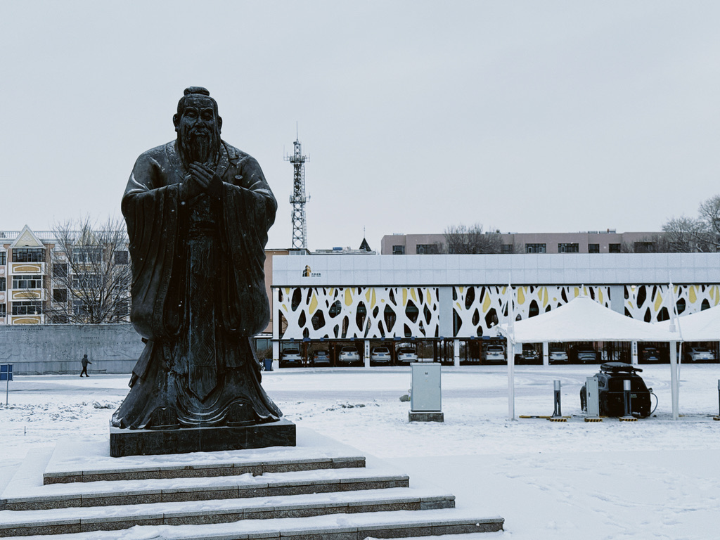 孔夫子雕像和背后在棚子下面充电的理想 ONE