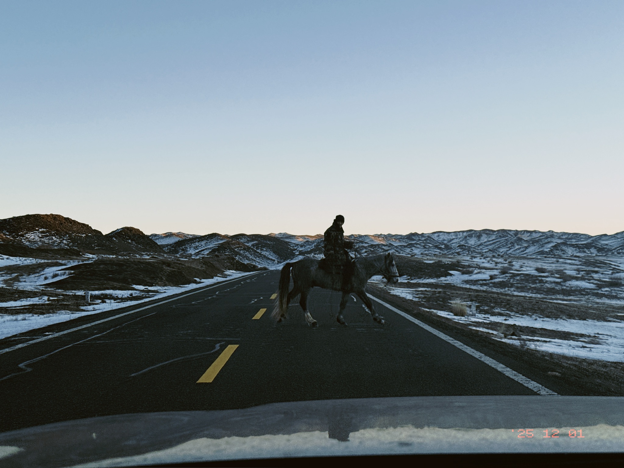 路上遇到一位牧民骑着马赶骆驼过马路，看到我们在拍还跟我们打招呼