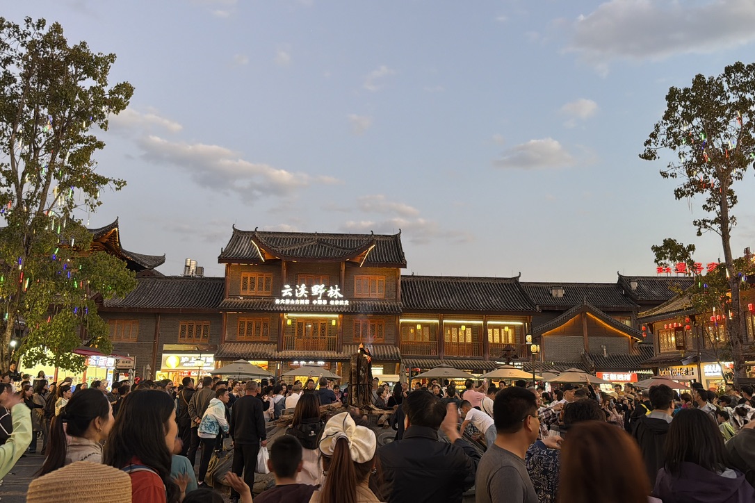 广场的中心则有人围着篝火在跳那种转圈圈的舞蹈，像我们在芒市广场上看到的那种