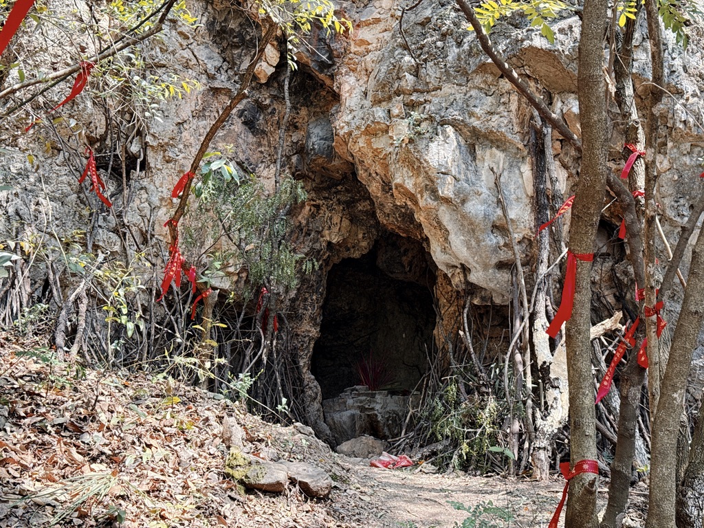 山腰中的一个小洞,里面自然有人烧香供奉,周围的石头下还支着木棍,也是一种祈福。