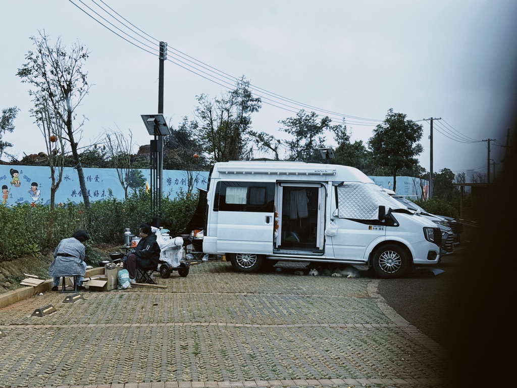 这里有房车在露营，两位老嫂子劈着木柴，做着烧饭的准备，一只巨大的哈士奇趴在车底下