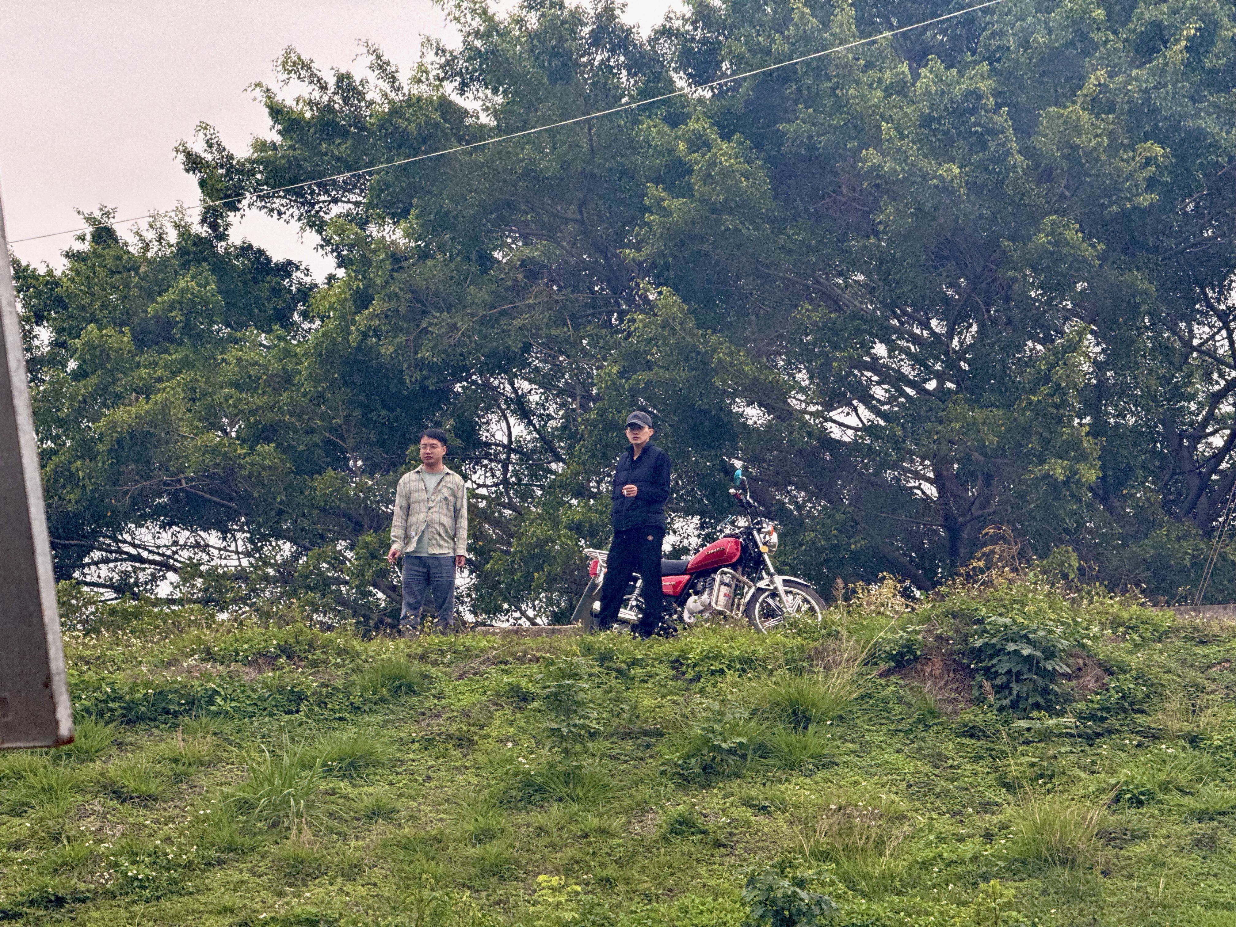 对面河堤上抽烟的两个人，背后停辆复古摩托，非常有电影感。